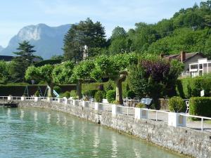 ein Fluss mit einer Stützmauer neben einem Haus in der Unterkunft Le Nid du Lac, appartement en duplex au bord du lac d'Annecy, résidence avec plage privée in Doussard