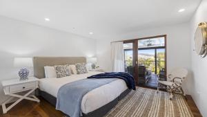 a bedroom with a bed and a chair and a window at Victoria's - Hamptons Beachside Residence in Emerald Beach