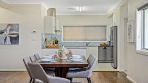 ein Esszimmer mit Tisch und Stühlen und eine Küche in der Unterkunft Sea Pine Cottage - In the heart of Sawtell Village, Sleeps 6 in Sawtell