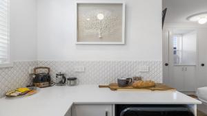 a kitchen with a white counter top with a picture on the wall at Sea Pine Studio - Sawtell Village & Beach Location in Sawtell