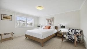 Un dormitorio blanco con una cama y una silla. en Ballantrae 8 - Walk To Beach & Cafes Sawtell Village, en Sawtell