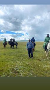 a group of people riding horses in a field at eco house "QUMUSH YURT" in Song-Kul