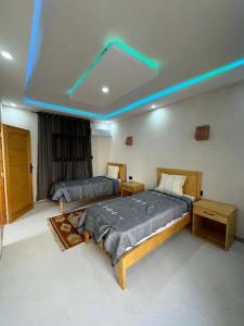 twee bedden in een kamer met blauwe lichten aan het plafond bij Dar FATMA in Houmt Souk