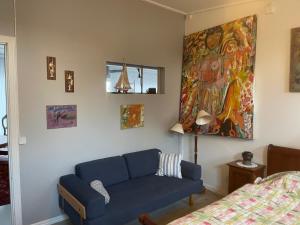 a living room with a blue couch and a painting at Skärhamns Paradis in Skärhamn