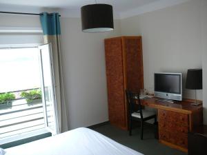 a bedroom with a desk with a television and a bed at Le Continental in Cancale