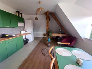 a kitchen with green cabinets and a table with chairs at Lemuria Pokoje Hostel Chojnowska A in Legnica
