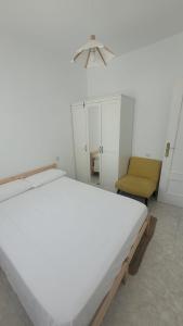 une chambre blanche avec un lit et une chaise dans l'établissement Casa Tonino: Encantadora casa junto al Río Duero, à Zamora