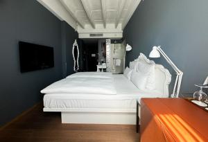 a bedroom with a white bed and a tv at Grand Ferdinand Vienna – Your Hotel In The City Center in Vienna