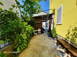 ザダルにあるApartment Rustica Zadar with exclusive use of the pool-ground floorのテーブルと椅子が置かれた黄色い建物のパティオ