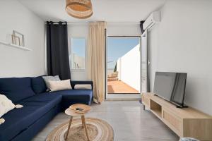 ein Wohnzimmer mit einem blauen Sofa und einem Fernseher in der Unterkunft Duplex marinero con vista al mar gimnasio piscina - LAS ABEJERAS 615 in Estepona