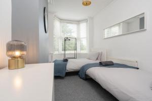 Un dormitorio con dos camas y una lámpara y una ventana. en Park House - By Sigma Stays, en Crewe