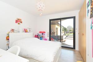a bedroom with a white bed and a sliding glass door at Villa Miluva - Maison climatisée avec piscine in Lapeyrouse-Fossat +14 photos