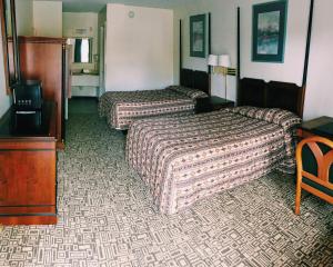 a hotel room with two beds and a television at Red Carpet Inn Kissimmee in Kissimmee