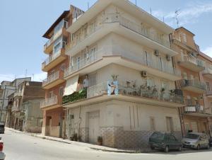 a tall building with balconies and cars parked on a street at Da Nonna Melina by Holiday World in Licata
