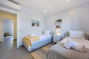 two beds in a room with white walls at O Golfinho in Lagos +18 photos