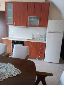 a kitchen with a white refrigerator and wooden cabinets at Anzhela apartment in Nea Roda +4 photos