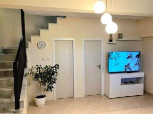 a living room with a tv and a clock on the wall at Anzhela apartment in Nea Roda