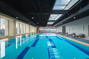 a large swimming pool with blue water in a building at Sheraton Shanghai Pudong Riverside in Shanghai