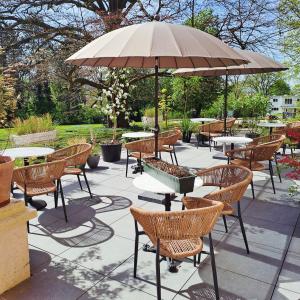 a patio with tables and chairs and an umbrella at Le Petit Château Peltzer in Verviers