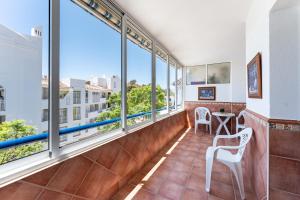 balkon z oknami, stołem i krzesłami w obiekcie Fuengirola Los Pacos Vistamar w mieście Fuengirola
