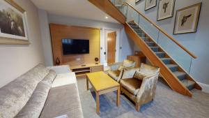 a living room with a couch and a tv and stairs at Oakley Hall Hotel in Basingstoke