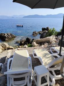 two chairs and an umbrella on a rocky beach at Villa Zvonimir in Sreser