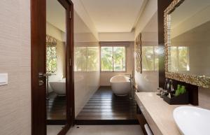 a bathroom with two tubs and two sinks and a mirror at MERUSAKA Nusa Dua in Nusa Dua