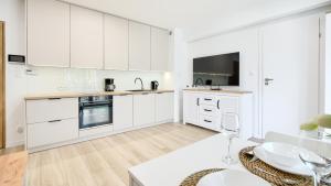 a white kitchen with white cabinets and a table at Horizon Park II, Sun & Snow in Dziwnówek