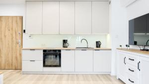 a white kitchen with white cabinets and a sink at Horizon Park II, Sun & Snow in Dziwnówek