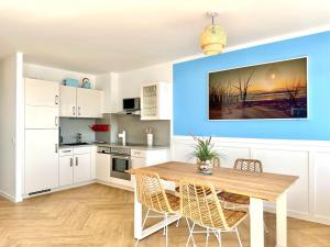 a kitchen and dining room with a wooden table and chairs at FeWo Traumblick - Himmel & Meer mit TRAUM Meerblick am Strand mit großem Balkon - WLAN, Streaming, 2024 modernisiert in Sierksdorf