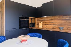 a kitchen with a white table and blue chairs at PERLA VERDE Apartments in Krk