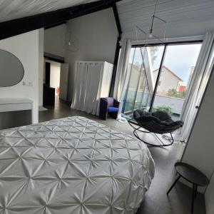 a bedroom with a large bed and a chair in it at Loft élégant,spacieux,atypique in Colombes +24 photos