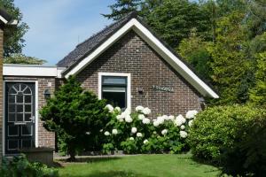 een klein bakstenen huis met witte rozen in de tuin bij Vakantiewoning 't Stookhok Gasselte in Gasselte