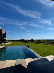 a swimming pool next to a grassy field with a house at Le Clos Vercheron in Artaix