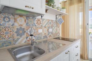 a kitchen with a sink and a tile wall at Agri Lemon Green in Pachino +69 photos