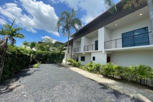 Casa blanca con entrada y palmeras en Alisse Stay Phuket Layan, en Phuket