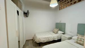 a small bedroom with two beds and a lamp at Estudio de Mia in Cádiz