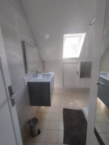 a white bathroom with a sink and a window at Maison de la fontaine in Saint-Méloir-des-Ondes