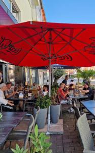 a group of people sitting at a restaurant under a red umbrella at Apartment am Konzerthaus in Dortmund