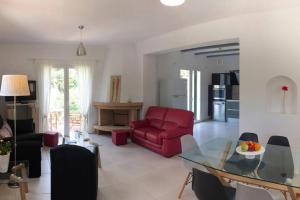 a living room with a red chair and a glass table at Villa Verde with Outdoor Jacuzzi in Divarata +20 photos