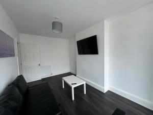 a living room with a couch and a tv on a wall at Theo apartment 150 meters from the winter gardens large groups welcome in Blackpool +7 photos