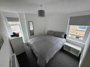 a white bedroom with a bed and two windows at Theo apartment 150 meters from the winter gardens large groups welcome in Blackpool