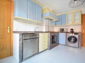 a kitchen with blue cabinets and a washer and dryer at GALIHOST - Apartamento en el casco histórico de Cambados in Cambados