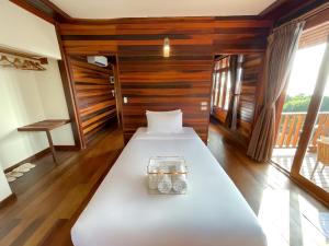 a room with a bed with a wooden wall at Dusit Buncha Koh Tao by Riya Group in Ko Tao