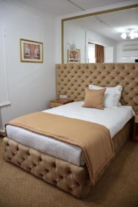 a large bed with a large headboard in a bedroom at Kurmet Hotel in Oral