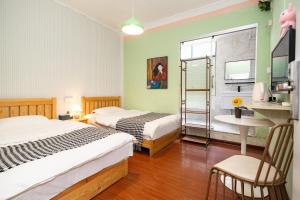 a bedroom with two beds and a table and a chair at Changsha Fuxiangyuan International Hostel in Changsha