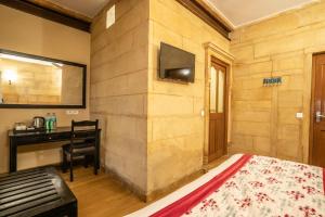 a room with a bed and a desk and a television at Naman Haveli-Boutique Stay For Budget Travllers in Jaisalmer