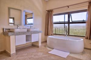 La salle de bains est pourvue d'une baignoire, de 2 lavabos et d'une fenêtre. dans l'établissement Sleeping Warrior Camp Elementaita, à Nakuru 28 autres photos