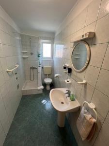 een badkamer met een wastafel, een toilet en een spiegel bij Apartmani Krunić in Barbat na Rabu