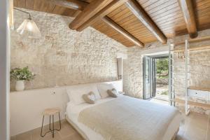una camera da letto con un letto bianco in un muro di pietra di Trullo Felicità a Putignano Altre 27 foto